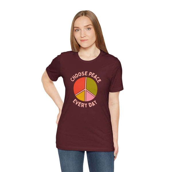 Model wearing Choose Peace Every Day Premium Soft Tee with colorful peace symbol on maroon fabric.