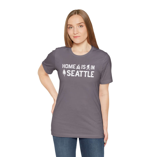 Home Is in Seattle Tee model wearing a gray shirt with the phrase 'Home is in Seattle' and evergreen designs.