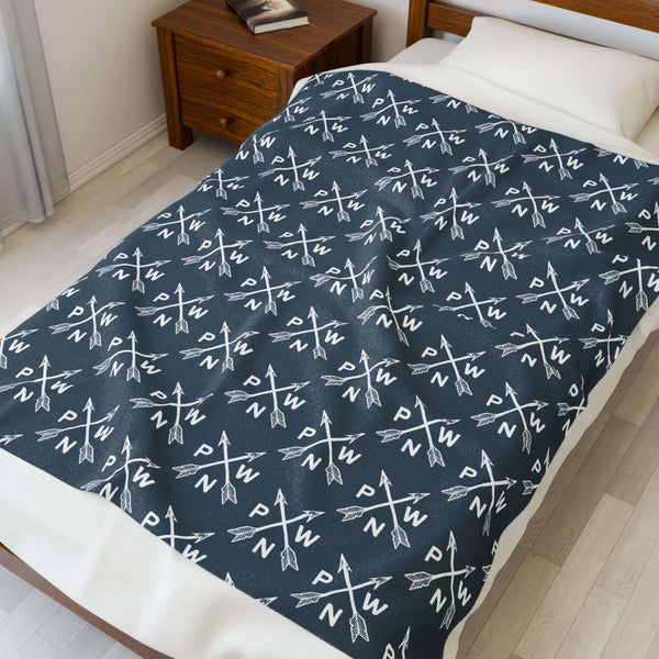 PNW Arrow Crossroads Lightweight Cozy Blanket featuring crossed arrows design on bed.