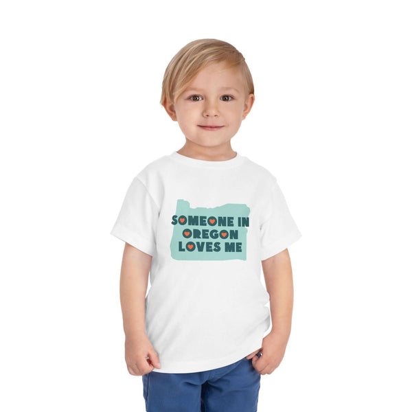 Someone in Oregon Loves Me Premium Soft Toddler Tee worn by a smiling child.