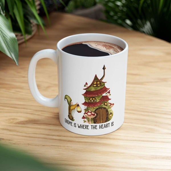 Gnome Is Where The Heart Is ceramic mug with gnome and mushroom house design, perfect for cozy beverages.