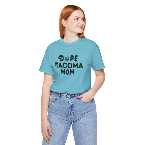 Woman wearing a blue "Dope Tacoma Mom" tee with a marijuana leaf design, showcasing unique style for moms in Washington state.