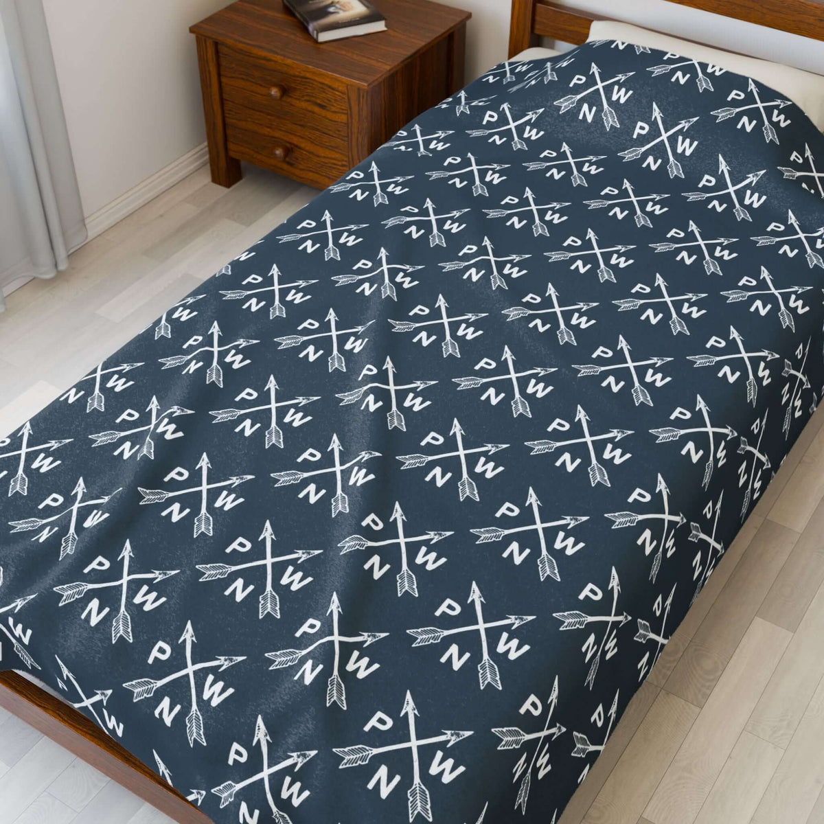 PNW Arrow Crossroads Lightweight Cozy Blanket with crossed arrows in a stylish pattern on a bed.