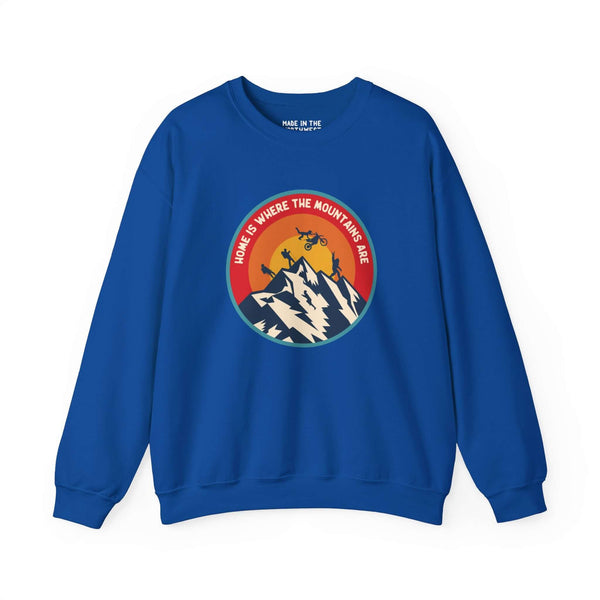 Blue sweatshirt featuring a colorful circle design with mountains, motocross, hiking, and Bigfoot, captioned "Home is Where the Mountains Are".