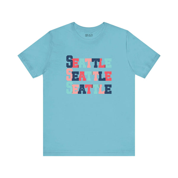 Bold and vibrant Seattle trio design tee in colorful block letters on light blue fabric, perfect for fans of Emerald City.