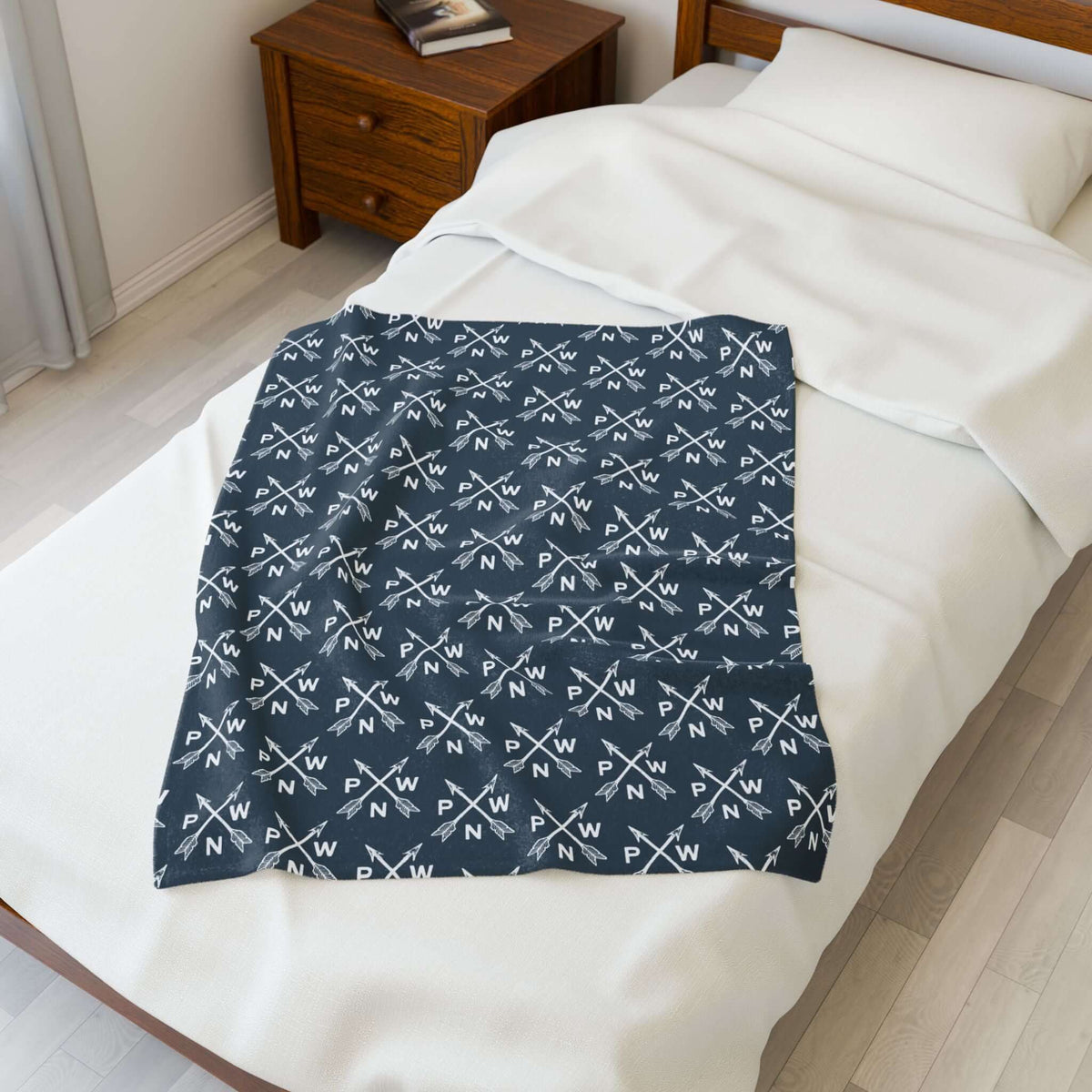 PNW Arrow Crossroads Lightweight Cozy Blanket displayed on a bed, featuring a stylish design with crossed arrows.
