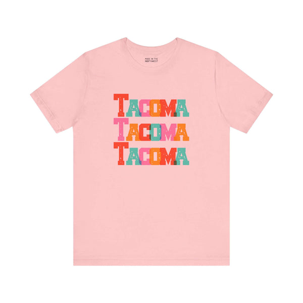 Pink Tacoma Trio Soft Tee with colorful block-letter city name design, perfect for Tacoma fans seeking bold and vibrant style.