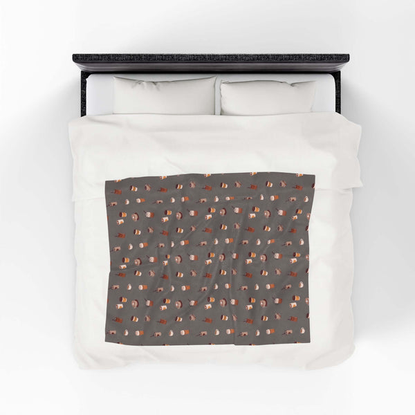 The Daily Grind Coffee Lovers Lightweight Cozy Blanket design with coffee cups on a comfy bedspread.