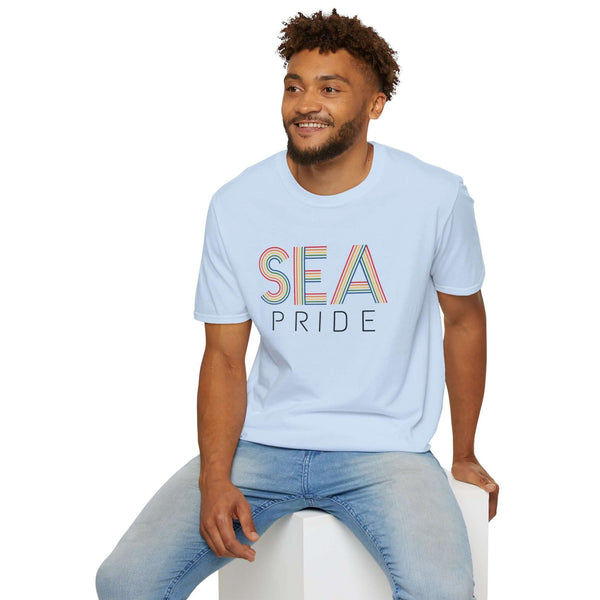 Man wearing a light blue SEA Pride t-shirt with rainbow letters, showcasing Seattle pride and community spirit.