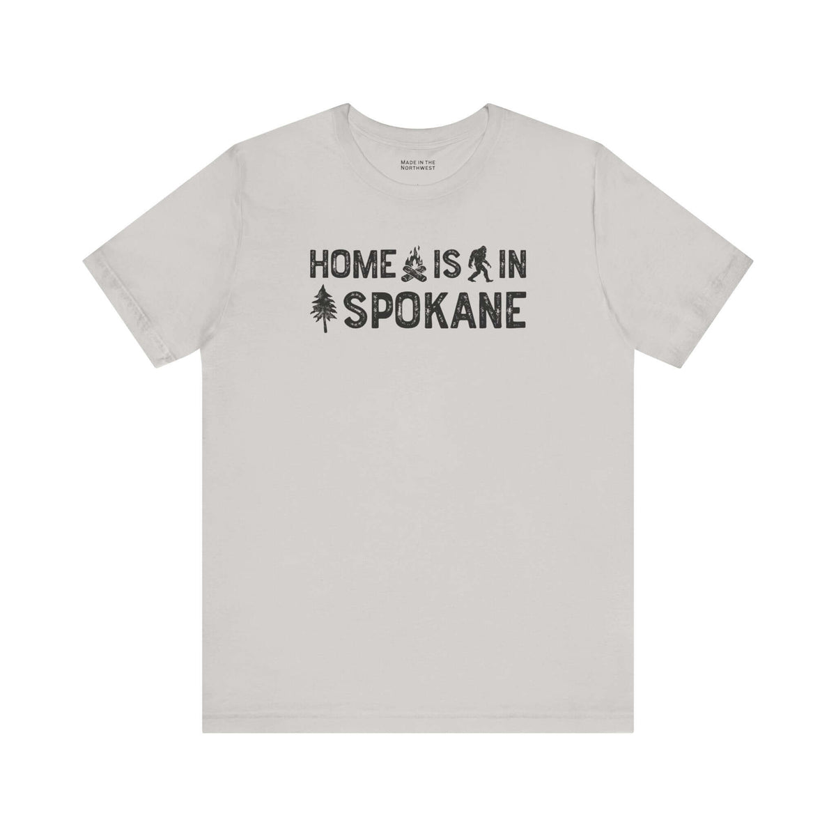 Home Is in Spokane Tee featuring campfire, Bigfoot, and tree illustrations celebrating Spokane's outdoor spirit.