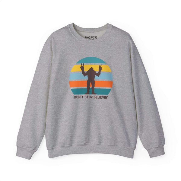 Don't Stop Believin' Bigfoot sweatshirt with playful sasquatch graphic and colorful sunset design.