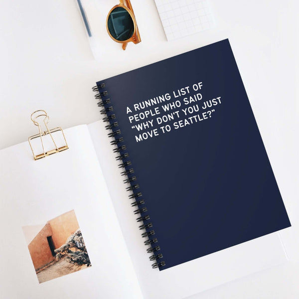 Spiral notebook featuring the text, "A running list of people who said 'Why don't you just move to Seattle?" on a desk.