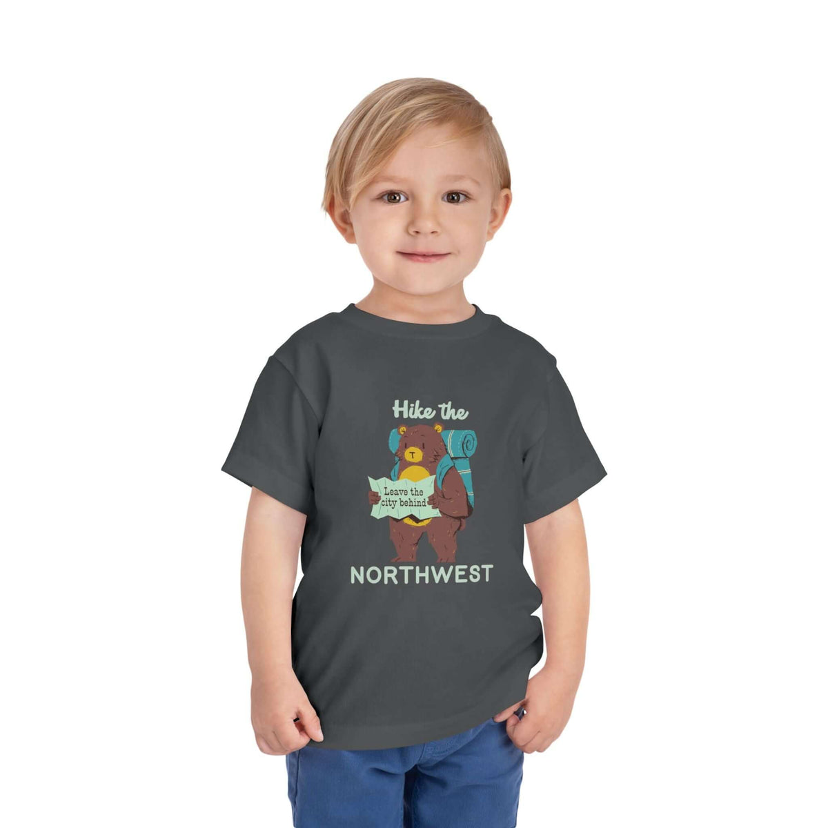 A toddler wearing a dark grey Hike the Northwest toddler tee featuring a bear with a map, perfect for little explorers.