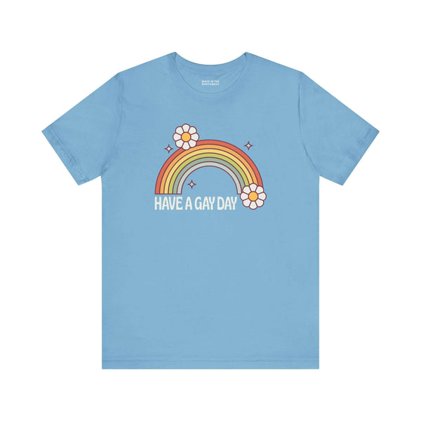Have a Gay Day T Shirt featuring a colorful rainbow and flowers on a light blue background.