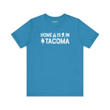 Home is in Tacoma tee in blue featuring campfire, Bigfoot, and tree designs to represent Tacoma's pride.