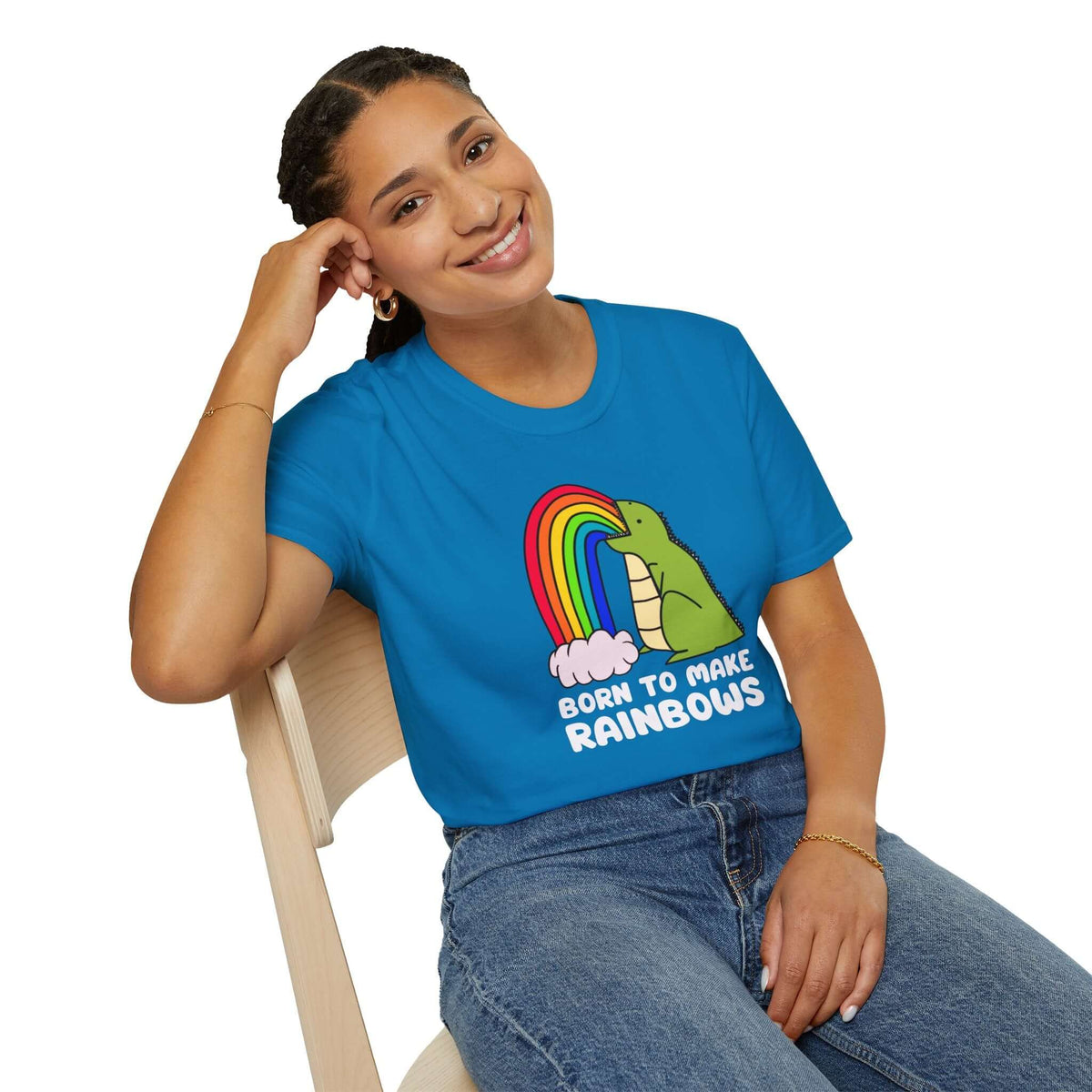 Person wearing a bright blue 'Born to Make Rainbows' dinosaur T-shirt with a rainbow graphic, embodying fun and uniqueness.