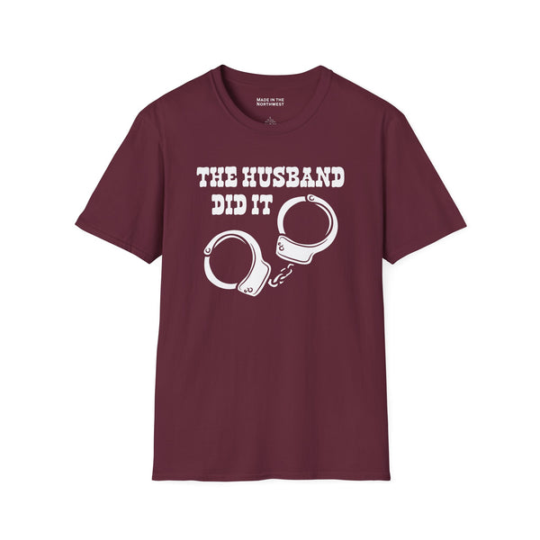 The Husband Did It T Shirt featuring bold text and a handcuff graphic on a maroon background.