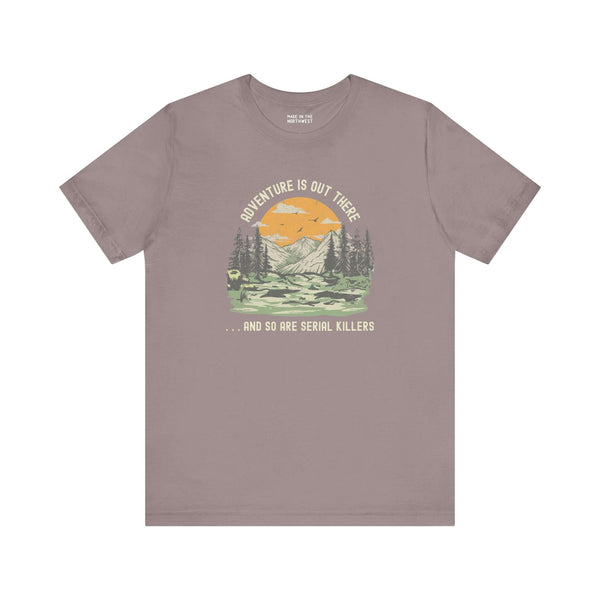 Premium soft tee featuring 'Adventure Is Out There... And So Are Serial Killers' design with mountains and trees.