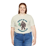 Woman wearing Don’t Be an Assquatch Tee featuring a friendly Bigfoot with flowers.