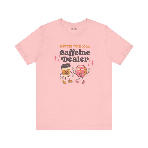 Pink soft tee with "Support Your Local Caffeine Dealer" text featuring cute coffee cup and donut graphics.