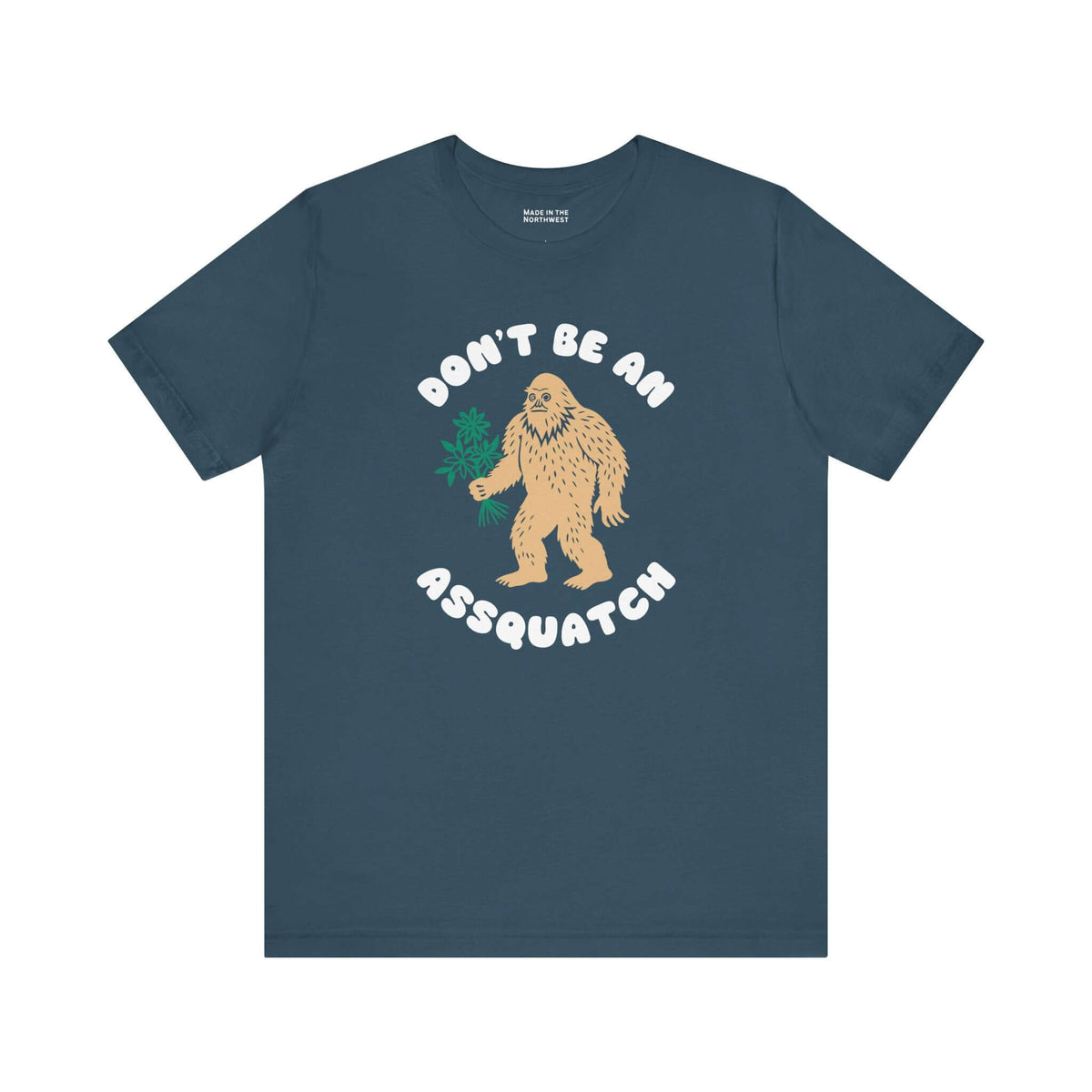 Don’t Be an Assquatch Tee featuring a friendly Bigfoot holding flowers on a navy shirt.