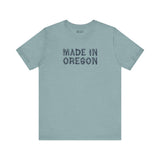Premium soft tee featuring rustic 'Made in Oregon' log font on a blue-green background, perfect for outdoor enthusiasts.