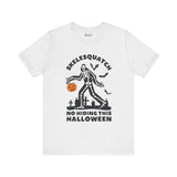 Skelesquatch Halloween tee with skeleton Sasquatch in graveyard holding a pumpkin bucket, text reads 