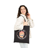 Model holding a black cotton tote bag with the text 