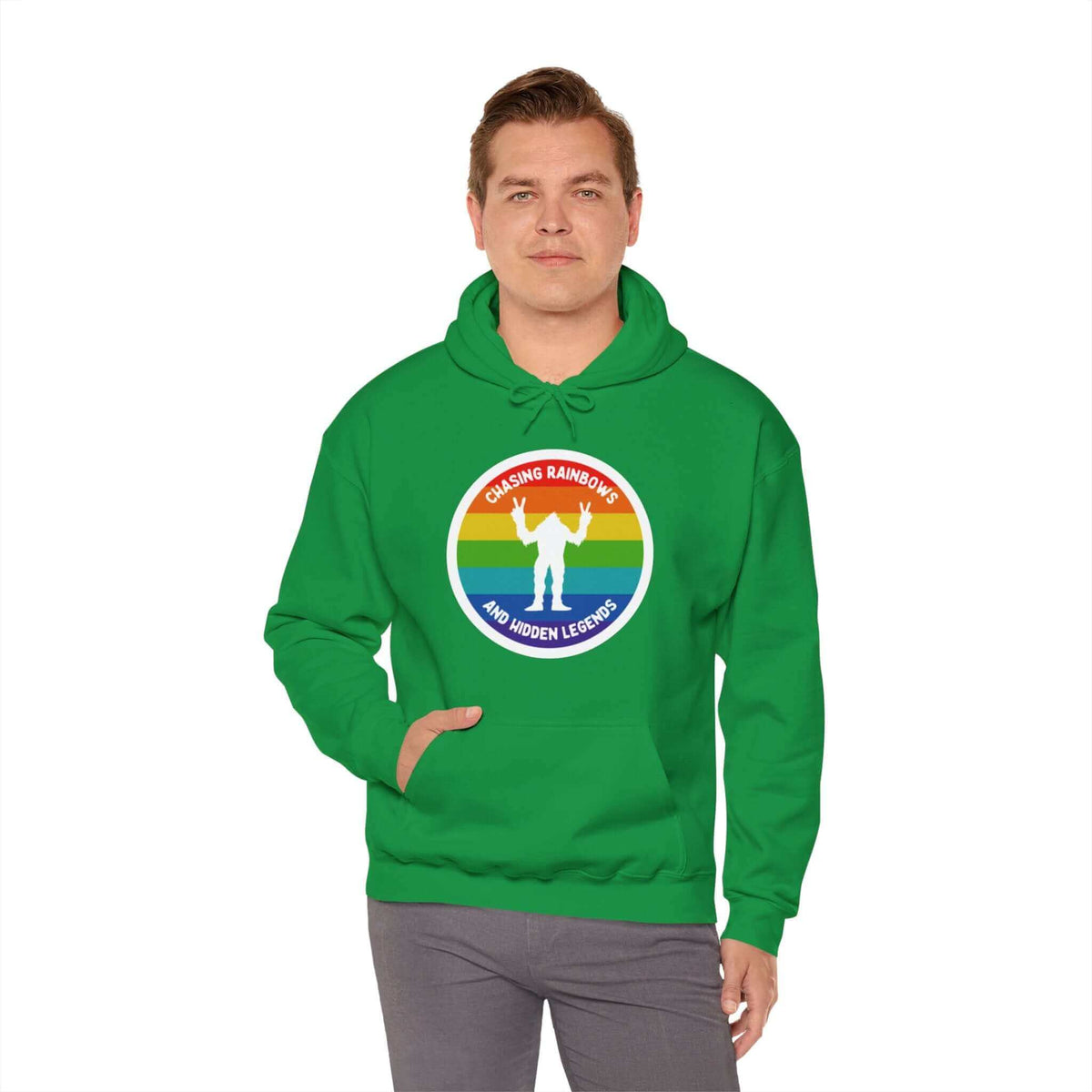 Man wearing green Chasing Rainbows Sasquatch Hoodie with colorful rainbow circle and playful Sasquatch graphic, celebrating PNW spirit.