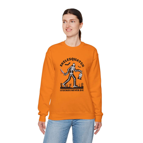 Woman wearing orange Skelesquatch sweatshirt with skeleton sasquatch graphic for Halloween.