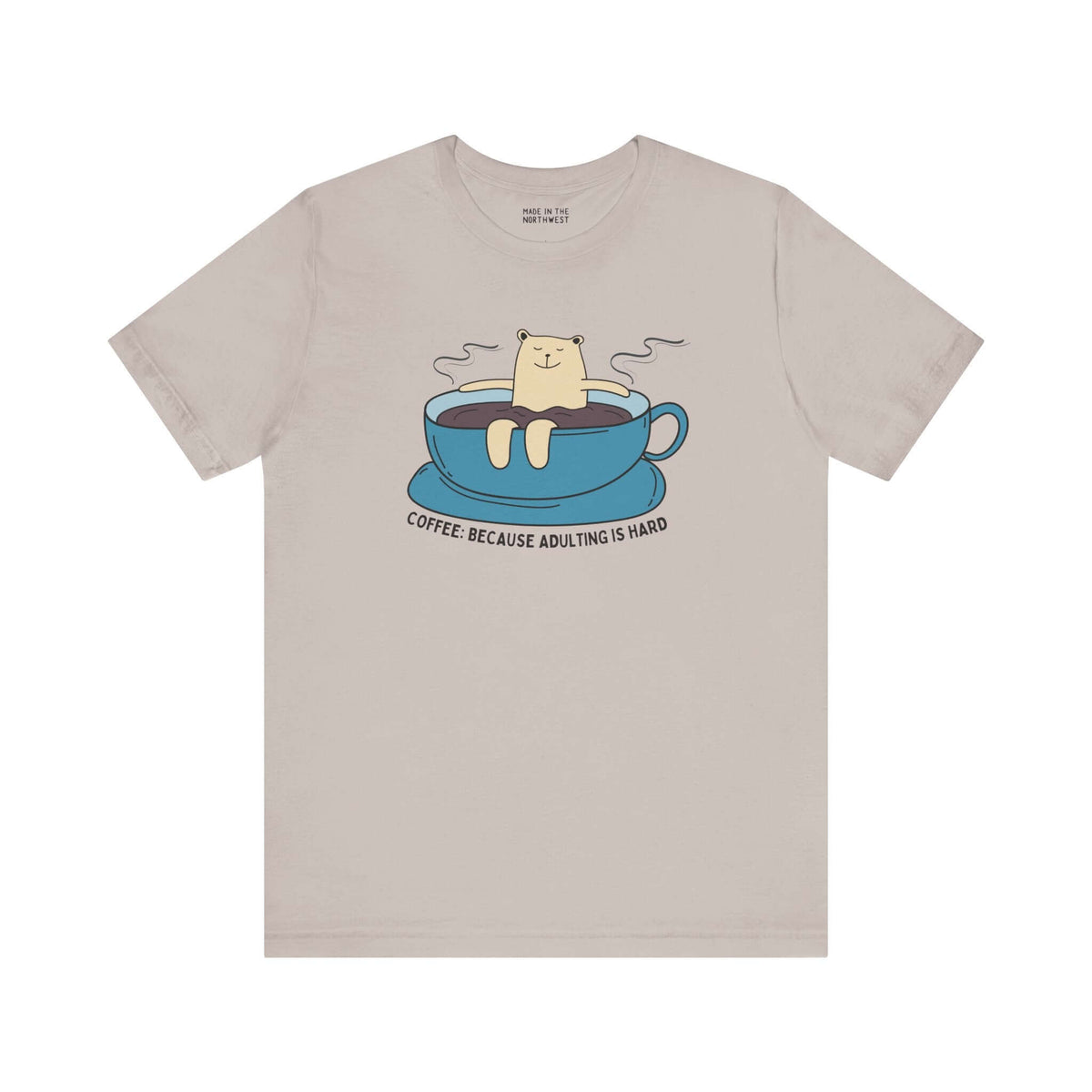 Premium soft tee featuring cute design with bear in coffee cup and text "Coffee Because Adulting Is Hard".