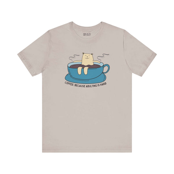 Premium soft tee featuring cute design with bear in coffee cup and text "Coffee Because Adulting Is Hard".