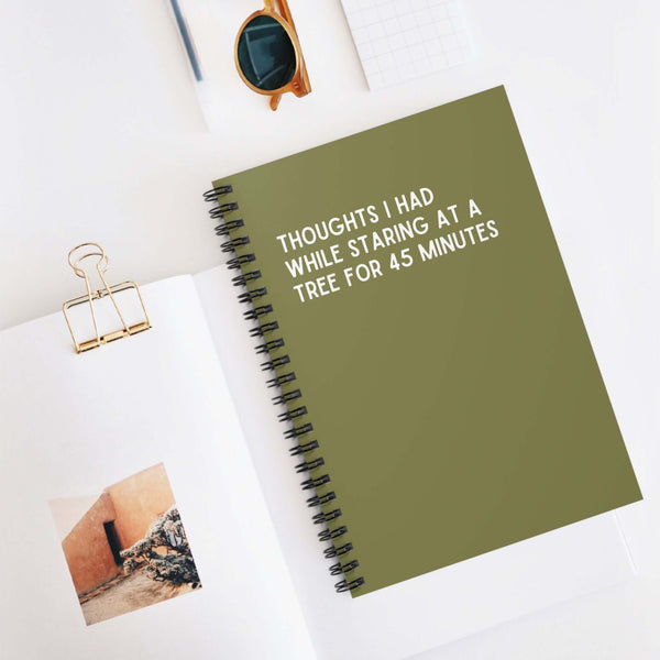 Spiral notebook with green cover titled 'Thoughts I Had While Staring at a Tree for 45 Minutes', perfect for recording inspirations.
