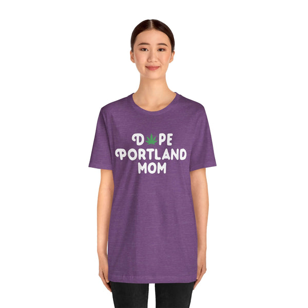 Woman wearing purple "Dope Portland Mom" tee with marijuana leaf design in 'O', showcasing unique PDX style for cool, laid-back moms.