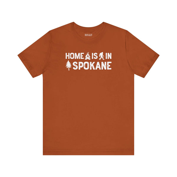 Home Is in Spokane Tee displayed on an orange t-shirt with outdoor designs.