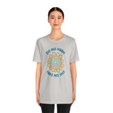 Model wearing a light gray Do No Harm Take No Shit Tee with a colorful peace flower design.