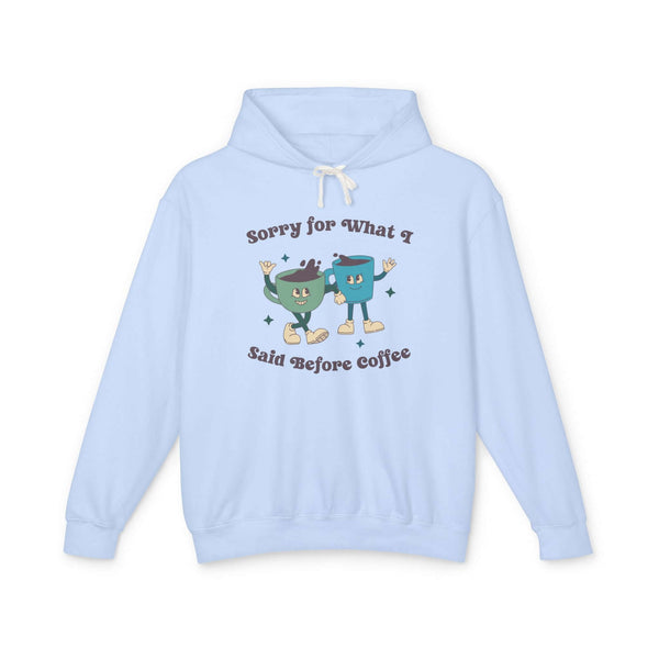 Light blue hoodie with playful graphic saying 'Sorry for What I Said Before Coffee' and cartoon coffee characters.
