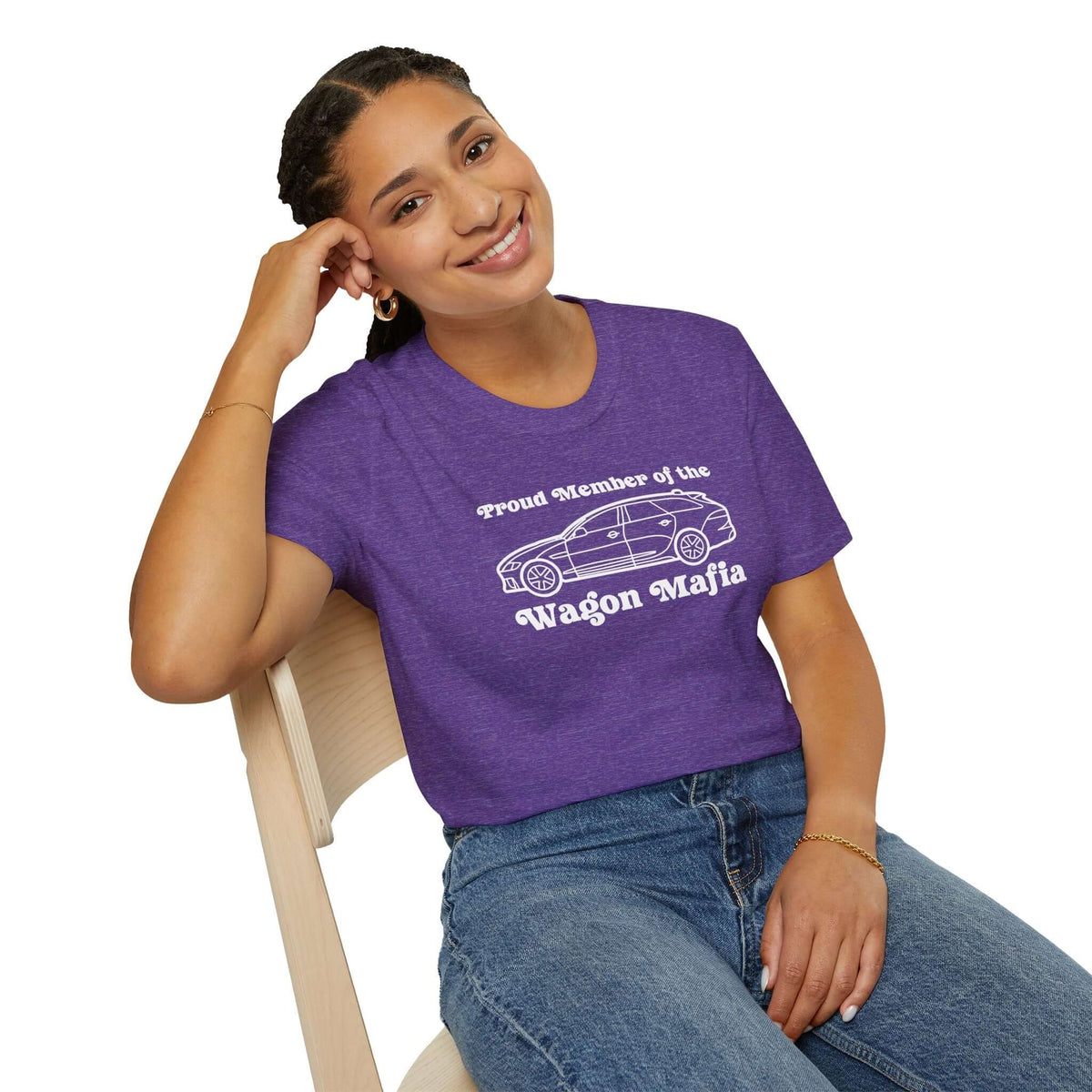 Smiling woman wearing a purple Proud Member of the Wagon Mafia t-shirt while sitting on a chair.