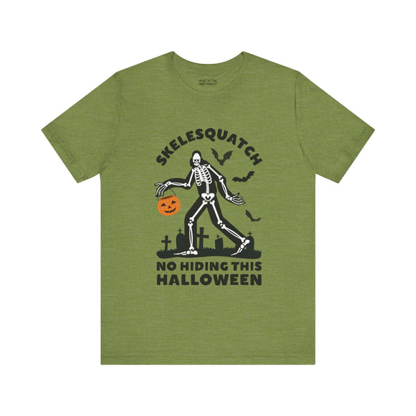 "Skelesquatch Halloween Soft Tee featuring skeleton Sasquatch with pumpkin bucket in graveyard on green shirt"