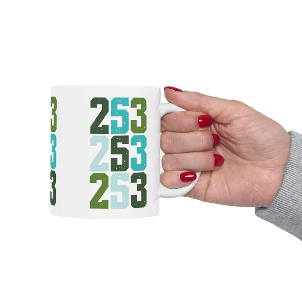 Hand holding a Two-Five-Three Pop Tacoma ceramic mug featuring vibrant 253 area code design.