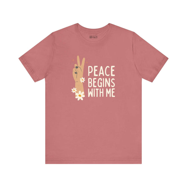 Rose-colored tee featuring peace sign and text 'Peace Begins With Me', promoting kindness and calm.
