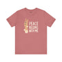 Rose-colored tee featuring peace sign and text 'Peace Begins With Me', promoting kindness and calm.
