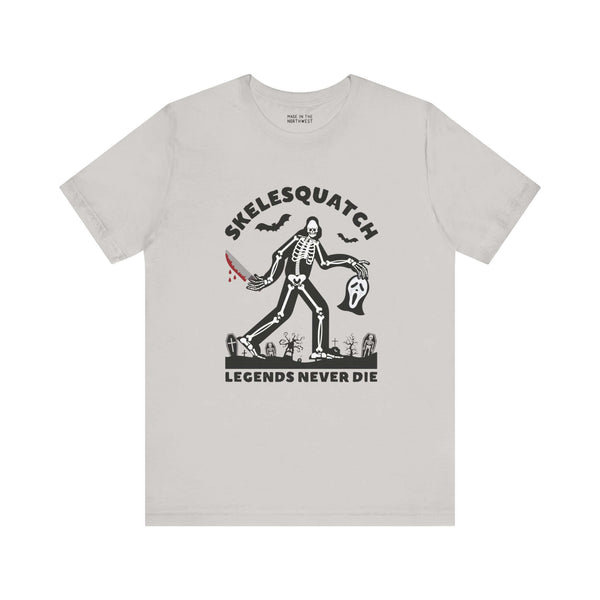 Skelesquatch Halloween tee featuring skeleton sasquatch with bloody knife and Scream mask in graveyard, perfect for cryptid and horror fans.