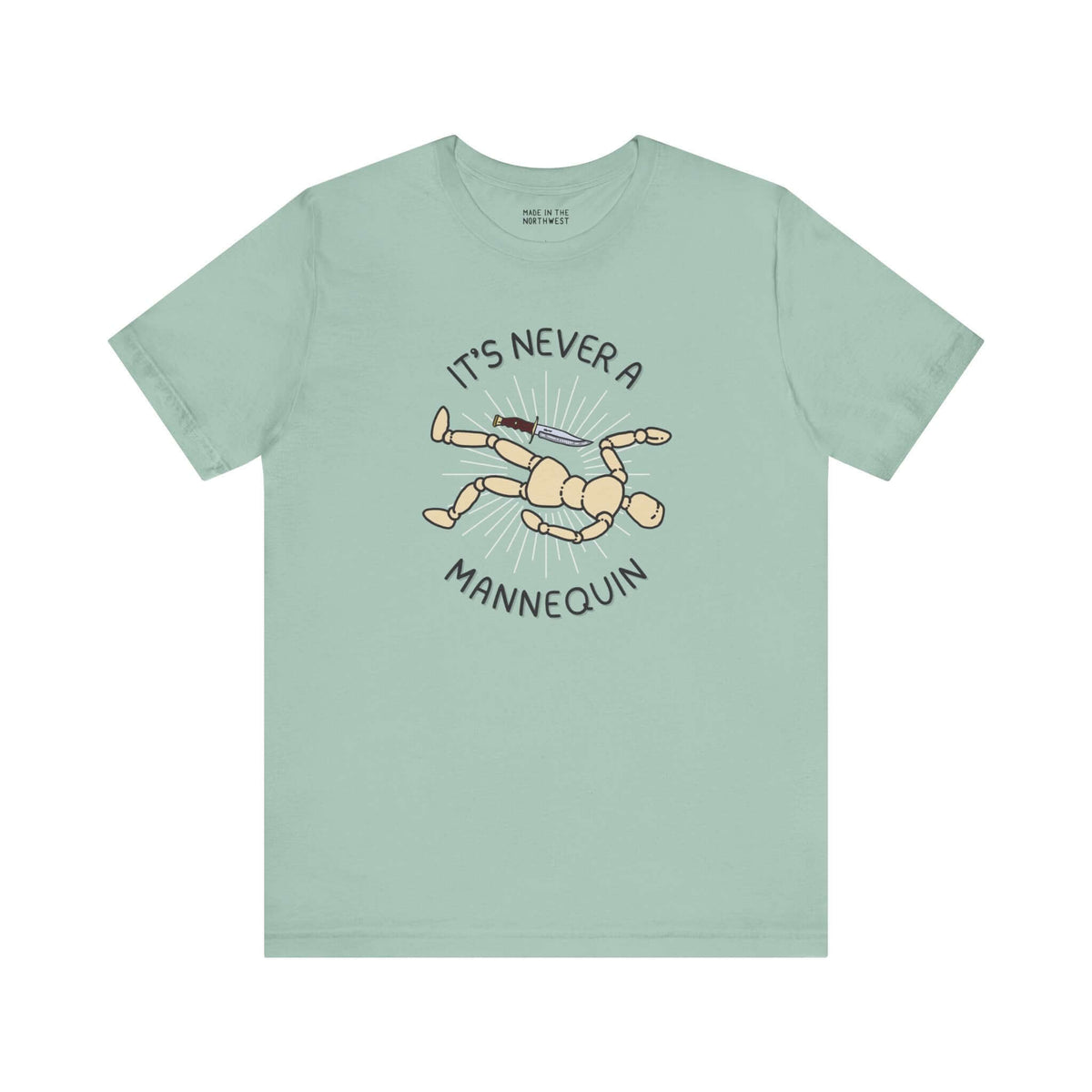 Mint green tee featuring graphic text 'It's Never a Mannequin' and cartoon mannequin, perfect for true crime fans.