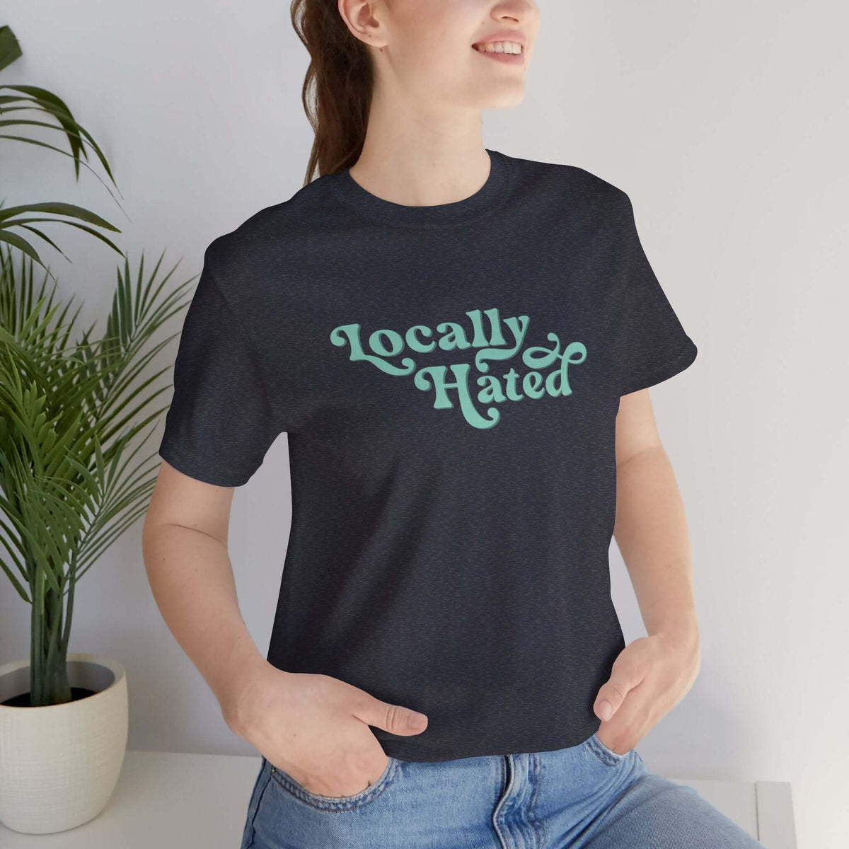 Woman wearing "Locally Hated" soft tee in bold cursive font, expressing a unique style and reputation statement.