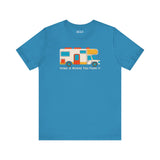 Home Is Where You Park It premium soft tee featuring a colorful RV graphic on a blue background.