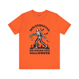 Orange Halloween tee featuring Skelesquatch skeleton Sasquatch with trick-or-treat bucket, bats, and graveyard design.