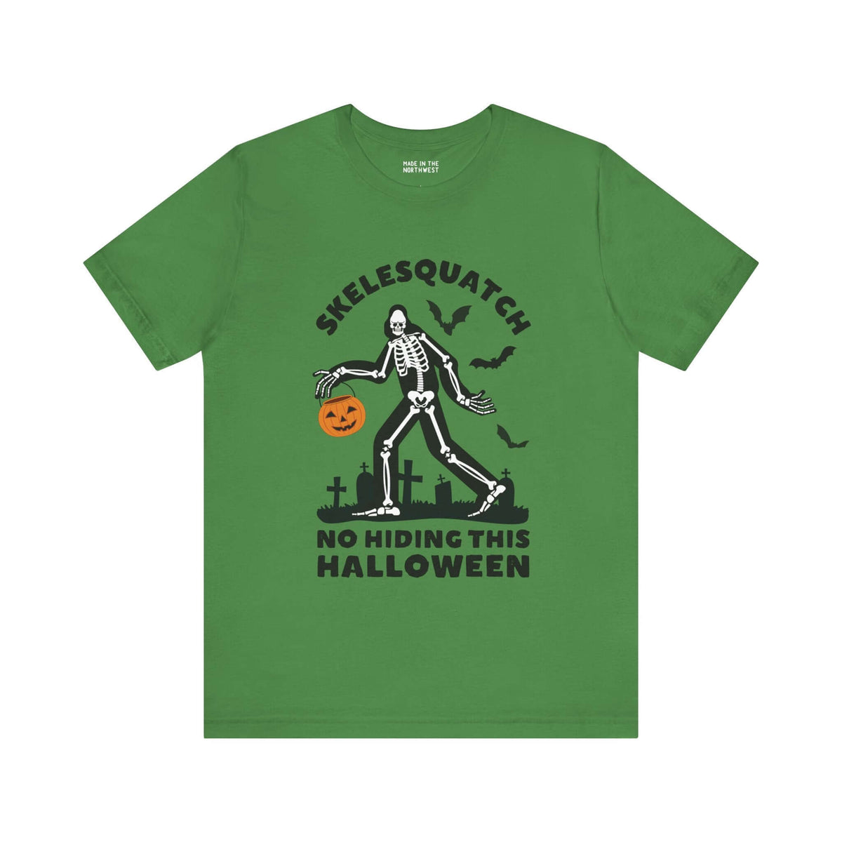 Green Halloween tee featuring Skelesquatch skeleton design with trick-or-treat bucket and graveyard, perfect for spooky celebrations.