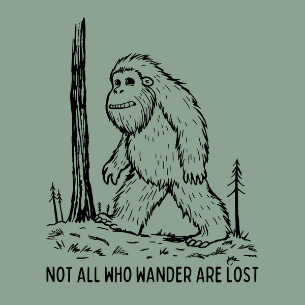 Bigfoot walking in the woods with the phrase 'Not All Who Wander Are Lost' on a softstyle t-shirt design.
