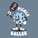 Playful pickleball character holding a paddle with text 'pickle baller' - perfect for pickle baller t shirt fans.